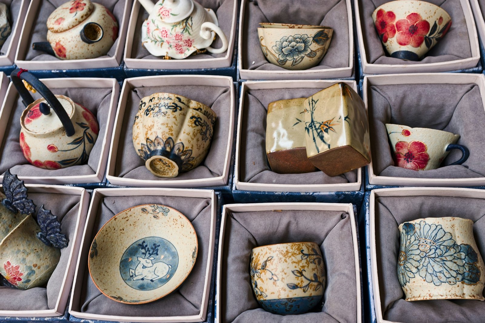 kodawari meaning — delicate ceramic tea cups and pots arranged with meticulous precision, evoking Japanese craft dedication